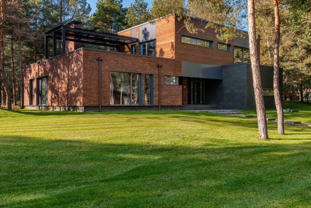 Contemporary house with large windows surrounded by lush greenery and trees.